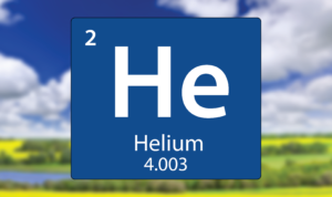 A graphic representation of the periodic table element Helium (He), with the atomic number 2 and atomic weight 4.003. The background features a blurred outdoor scene with a clear blue sky, white clouds, and a landscape of green fields and yellow flowers.