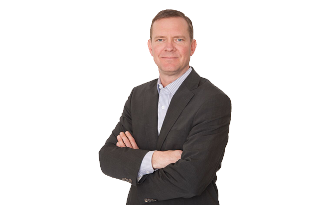 A portrait of Greg Meidinger, VP Land at Scott Land & Lease Ltd. He is wearing a dark suit with a light-colored shirt and is standing with his arms crossed, looking directly at the camera with a neutral expression. The background is plain white, highlighting his professional appearance.